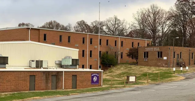 L'edificio in mattoni a più piani della Winston Salem Christian School con l'insegna lilla è circondato da alberi spogli.