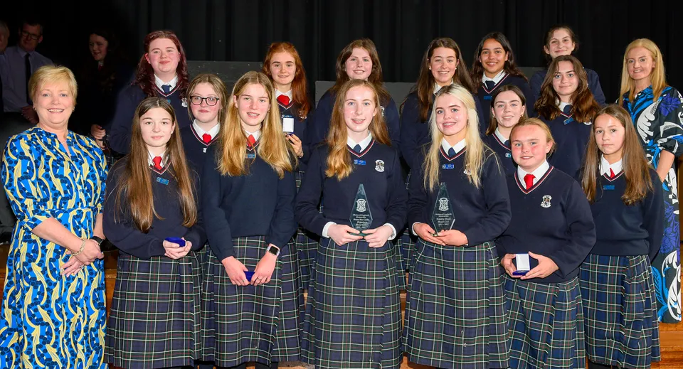 Un gruppo di studentesse della St. Louis Secondary School posa insieme davanti a una tenda scura.