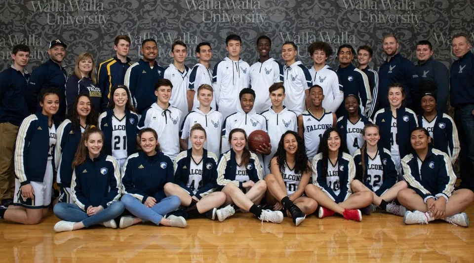 Un gruppo di giovani atleti e atlete nel centro sportivo della Auburn Adventist Academy posa insieme davanti al logo.