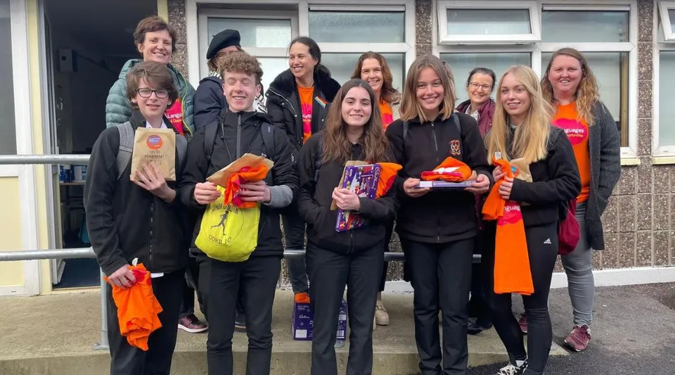 Un gruppo di studenti e studentesse in abiti colorati è radunato davanti a un edificio del campus del Colaiste Muire (Cobh).