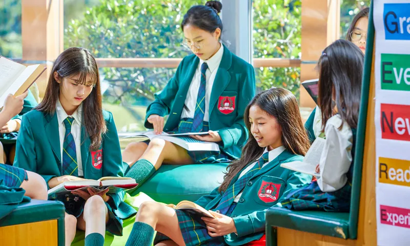 Schüler der Branksome Hall Asia sitzen im Klassenzimmer und lesen gemeinsam Bücher.