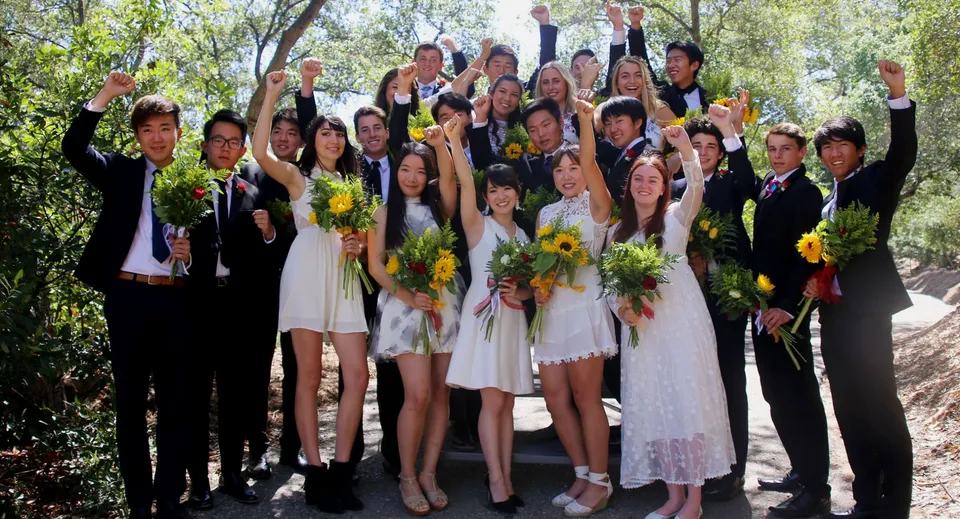 Un gruppo di studenti del Stanstead College in abiti eleganti festeggia all'aperto tenendo bouquet di fiori.