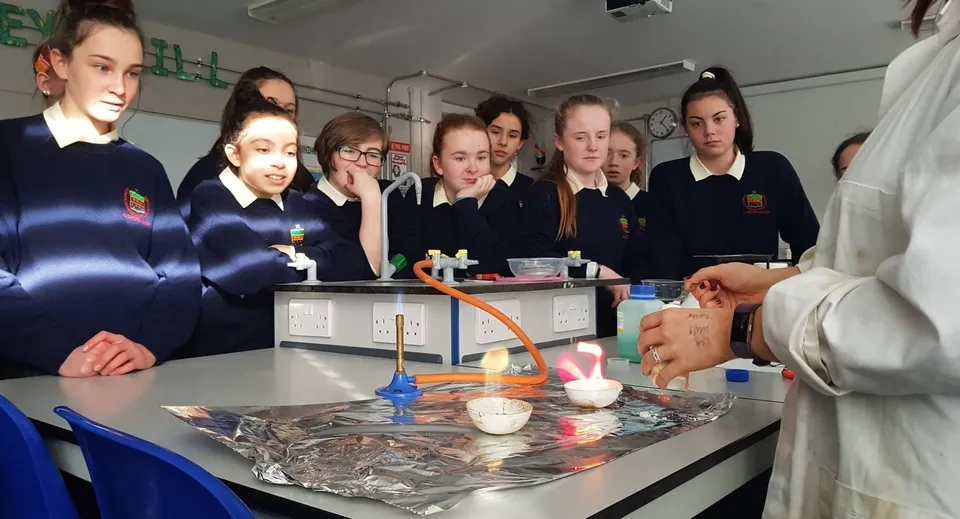 Studenti della Rockford Manor School osservano insieme un esperimento con strumenti da laboratorio al banco di scuola.
