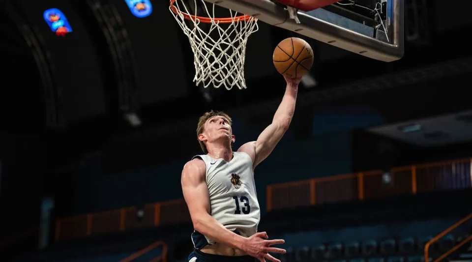 Un giocatore di basket salta per tirare a canestro sul campo della Royal Crown School.