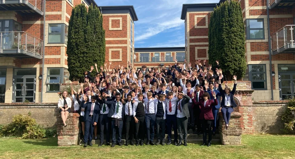 Un grande gruppo di studenti e studentesse posa per una foto di gruppo davanti a un edificio in mattoni della Royal Russell School con pareti coperte d'edera.