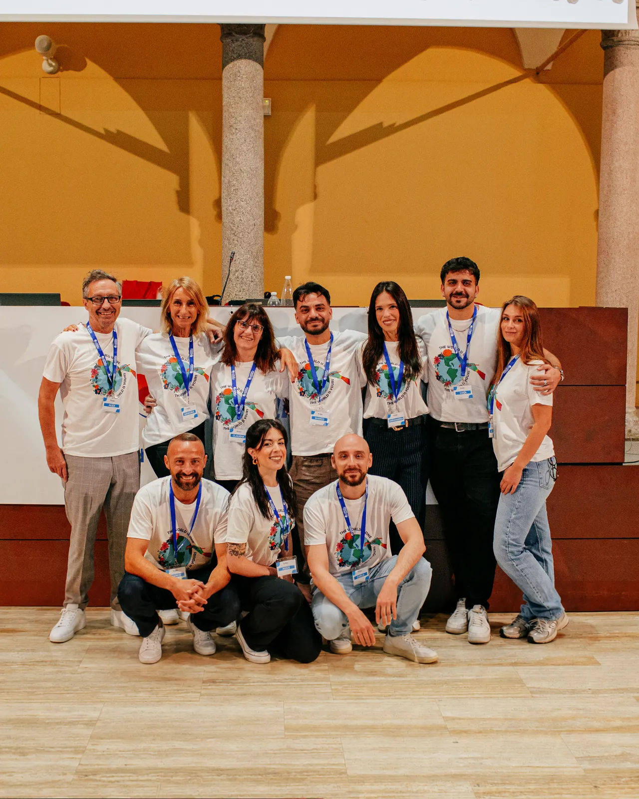 Gruppo di colleghi in magliette coordinate posa insieme sorridendo