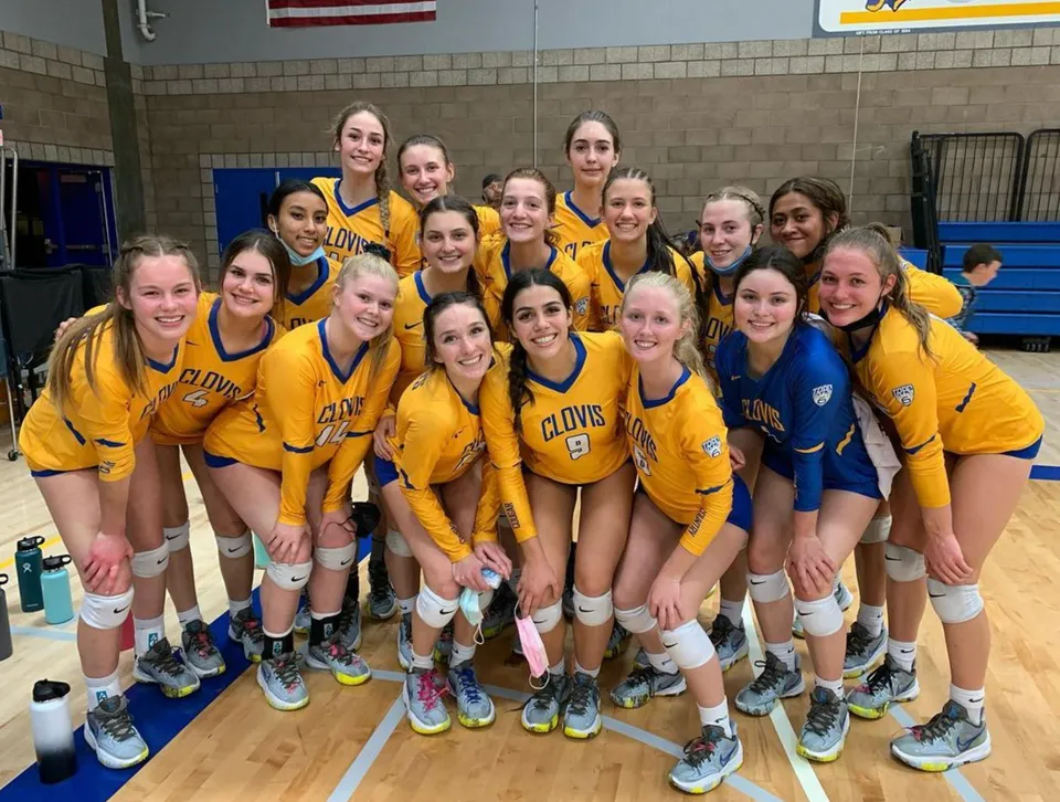 Studentesse della Clovis High School in divisa giallo-blu posano insieme nella palestra.