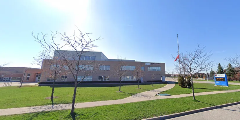 L'edificio moderno della Rick Hansen Secondary School con un prato e alberi spogli in primo piano sotto un cielo limpido.