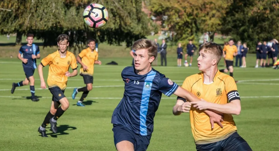 Studenti della Scoil Dara che giocano una partita di calcio su un campo erboso.