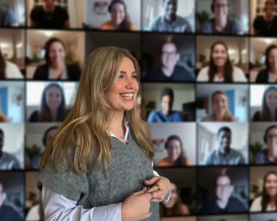 Chica sonriente ante la pantalla con los participantes de un seminario web
