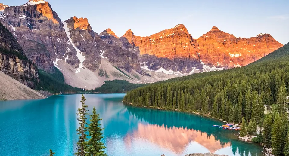 Una montagna innevata si erge sopra un lago turchese e un bosco di conifere nei pressi della Langley Fine Arts School.