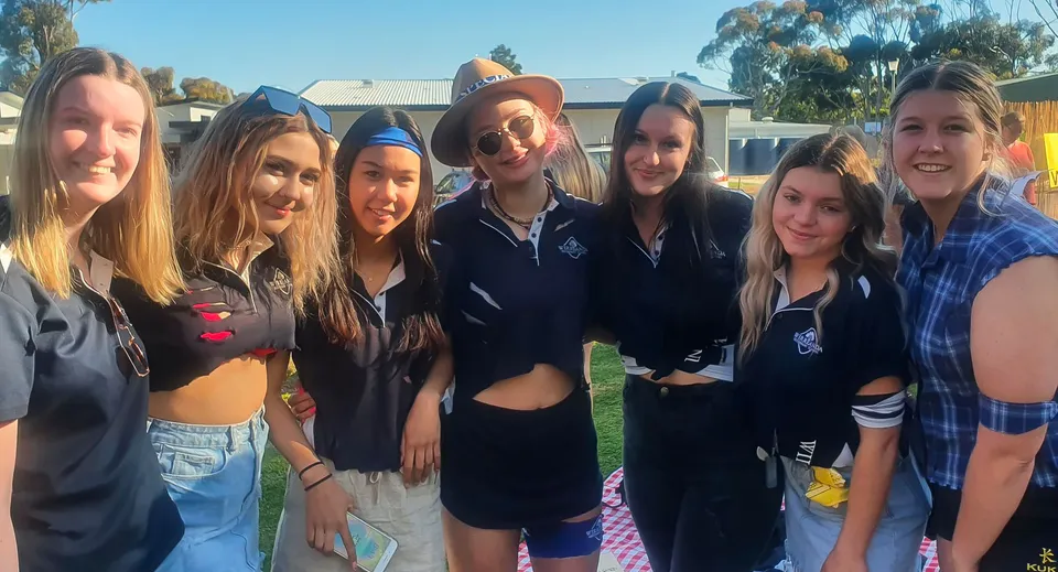 Un gruppo di studentesse si trova all'aperto nel campus della Wirreanda Secondary School davanti a un edificio e ad alcuni alberi.