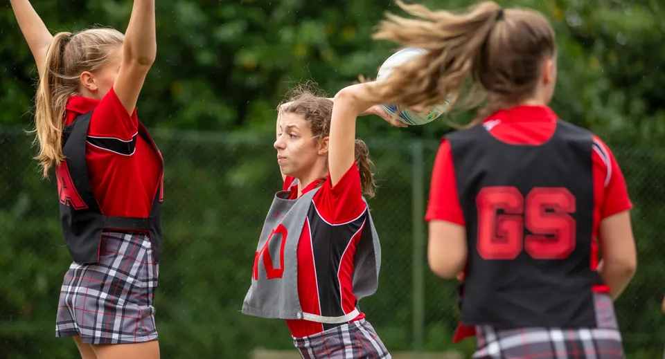 Tre giovani atlete della Somervale School si scaldano all'aperto su un prato.