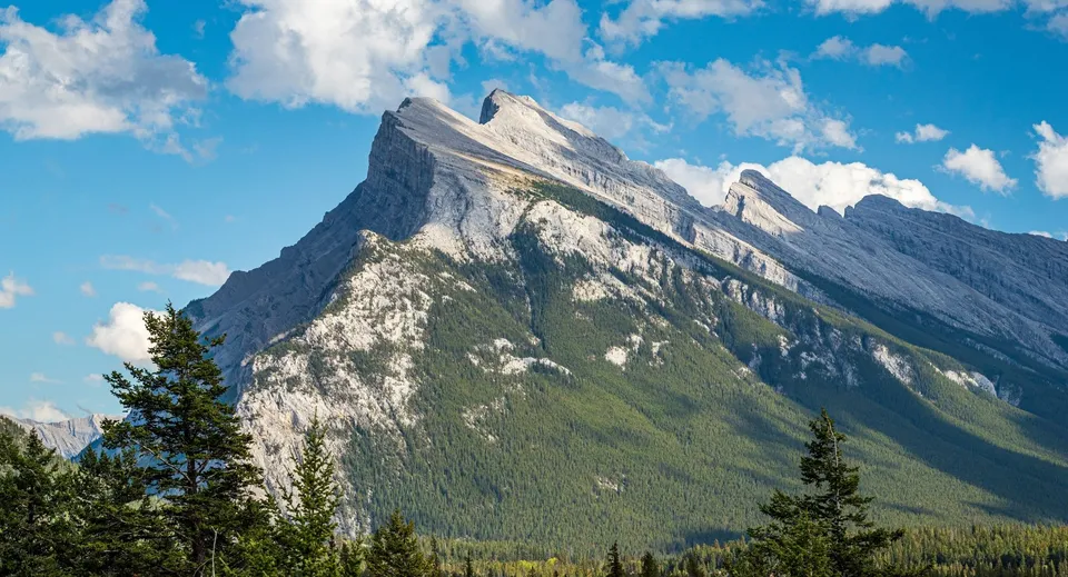 Maestose montagne innevate con cielo blu e foresta verde davanti alla Bernice McNaughton High School.