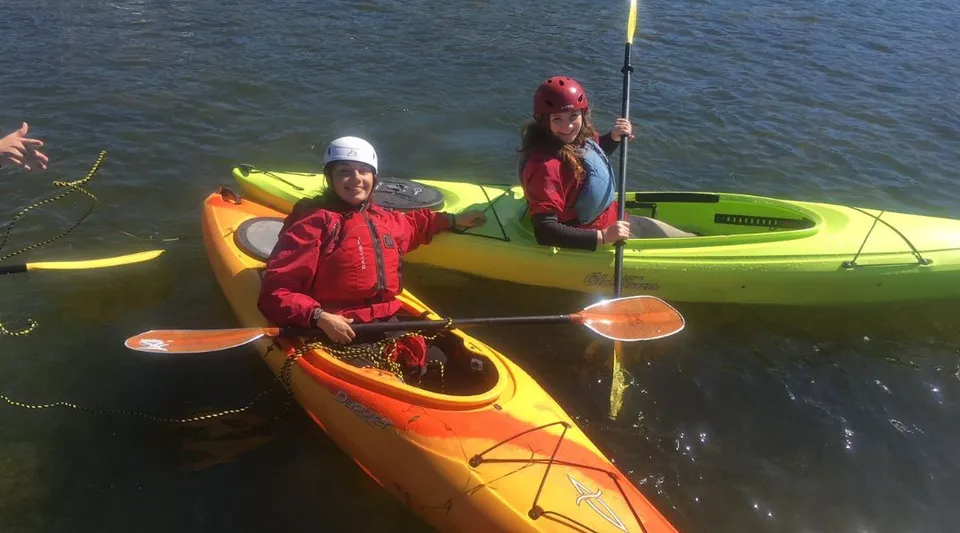 Due persone pagaiano su kayak colorati nell'acqua vicino alla Coalhurst High School.