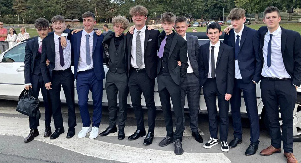Un gruppo di ragazzi in abiti formali si trova nell'area esterna della St. Mary’s Diocesan School con alberi e edifici sullo sfondo.
