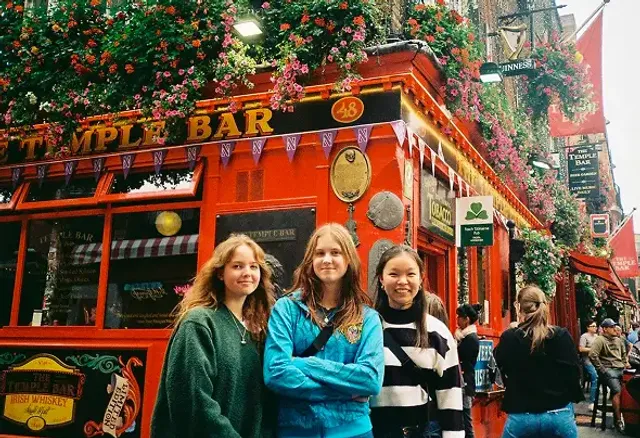 Tre ragazze sorridenti davanti al pub Temple Bar decorato con fiori a Dublino