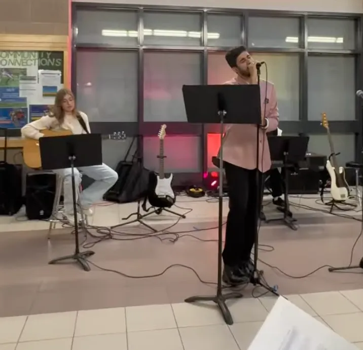 Ein Schüler singt und die andere Schülerin spielt dabei Gitarre