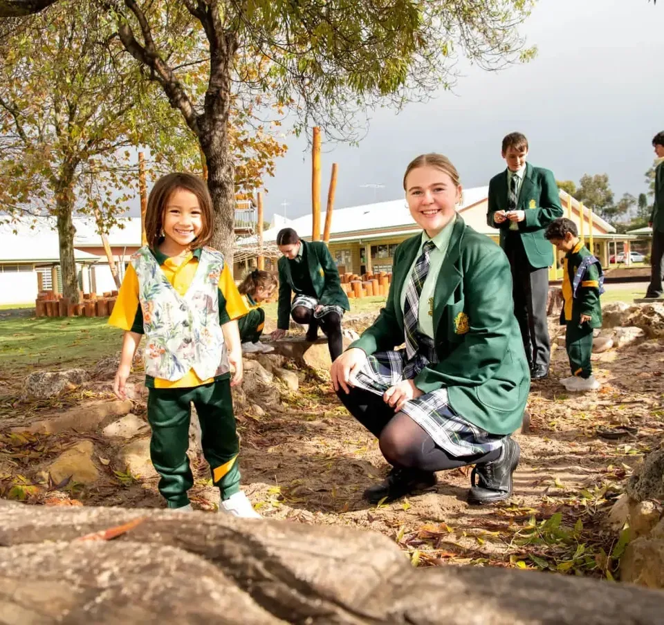 Studenti della Frederick Irwin Anglican School in divisa scolastica verde nell'area all'aperto del campus.