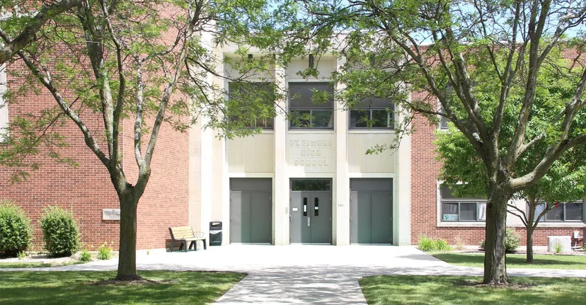 L'edificio moderno in mattoni con ampie finestre della St. Edmond Catholic School è circondato da una verde vegetazione e alberi.