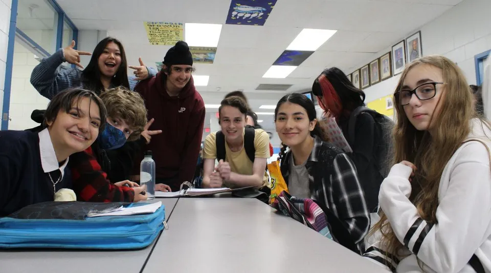 Un gruppo di studenti della Mount Elizabeth Middle/Secondary School siede attorno a un tavolo in classe e lavora insieme.