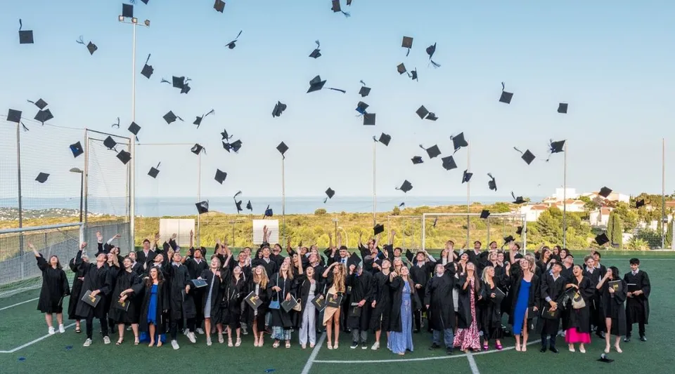 Studenti della Laude Lady Elizabeth School festeggiano la loro cerimonia di diploma sul campo sportivo lanciando i loro cappelli in aria.