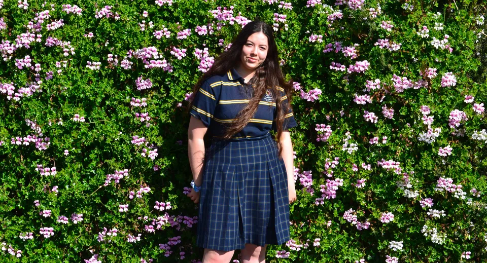 Una giovane donna si trova in un giardino verde con fiori rosa in fiore sul terreno del Plympton International College.