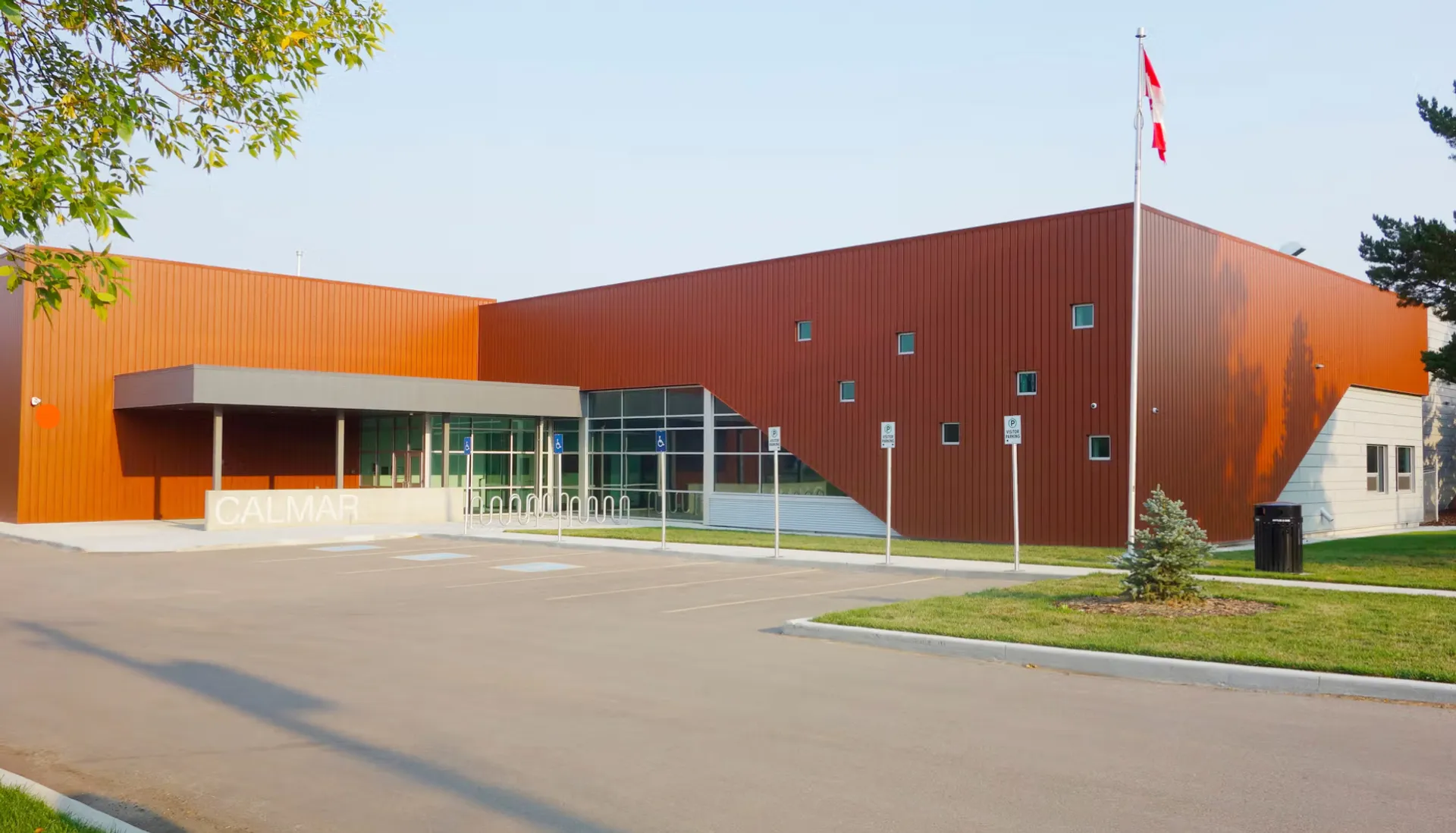 L'edificio della Calmar Secondary School con facciata metallica marrone, ampie vetrate e la bandiera canadese.