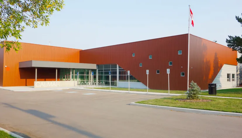 L'edificio della Calmar Secondary School con facciata metallica marrone, ampie vetrate e la bandiera canadese.