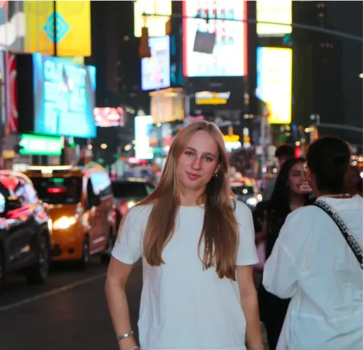 Ragazza in maglietta bianca posa a Times Square illuminata di notte a New York