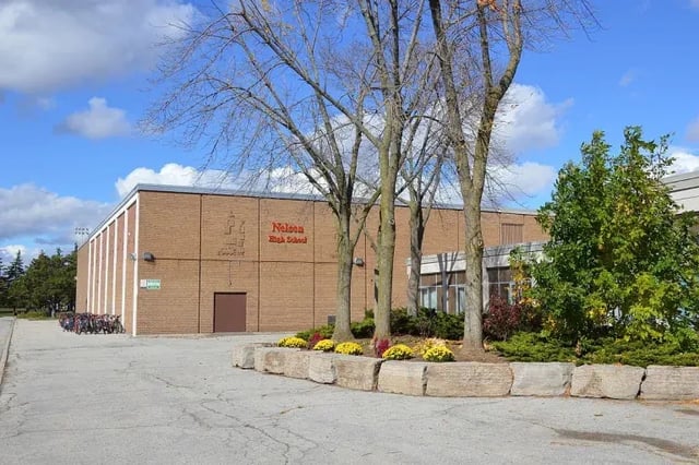 L'imponente edificio in mattoni della Nelson High School è circondato da alberi e aree verdi.