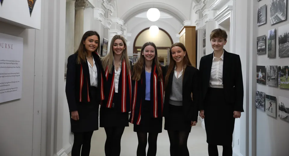 Cinque ragazzi in abito formale sono insieme nel corridoio del campus del Pangbourne College.