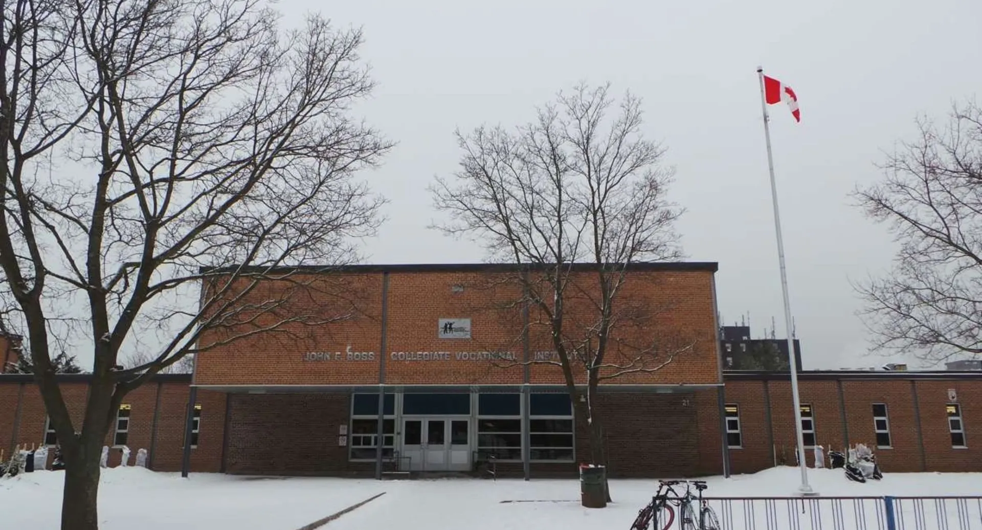 L'edificio in mattoni del John F. Ross Collegiate Vocational Institute in inverno con la neve e la bandiera canadese.