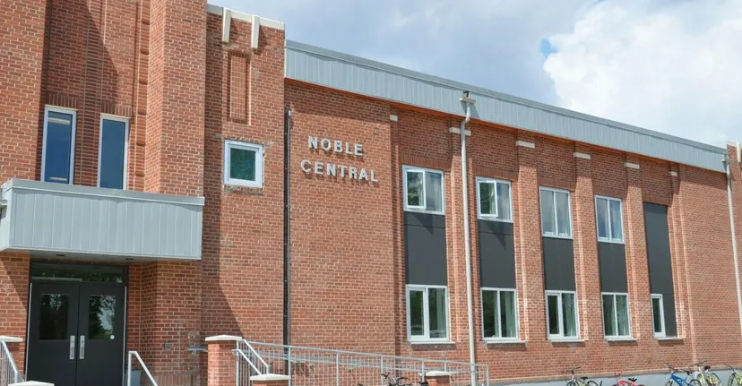 L'edificio in mattoni a più piani della Noble Central School sotto un cielo nuvoloso.