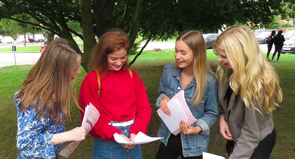 Quattro studentesse della St. Alban's Catholic High School sono immerse nel verde e stanno conversando.
