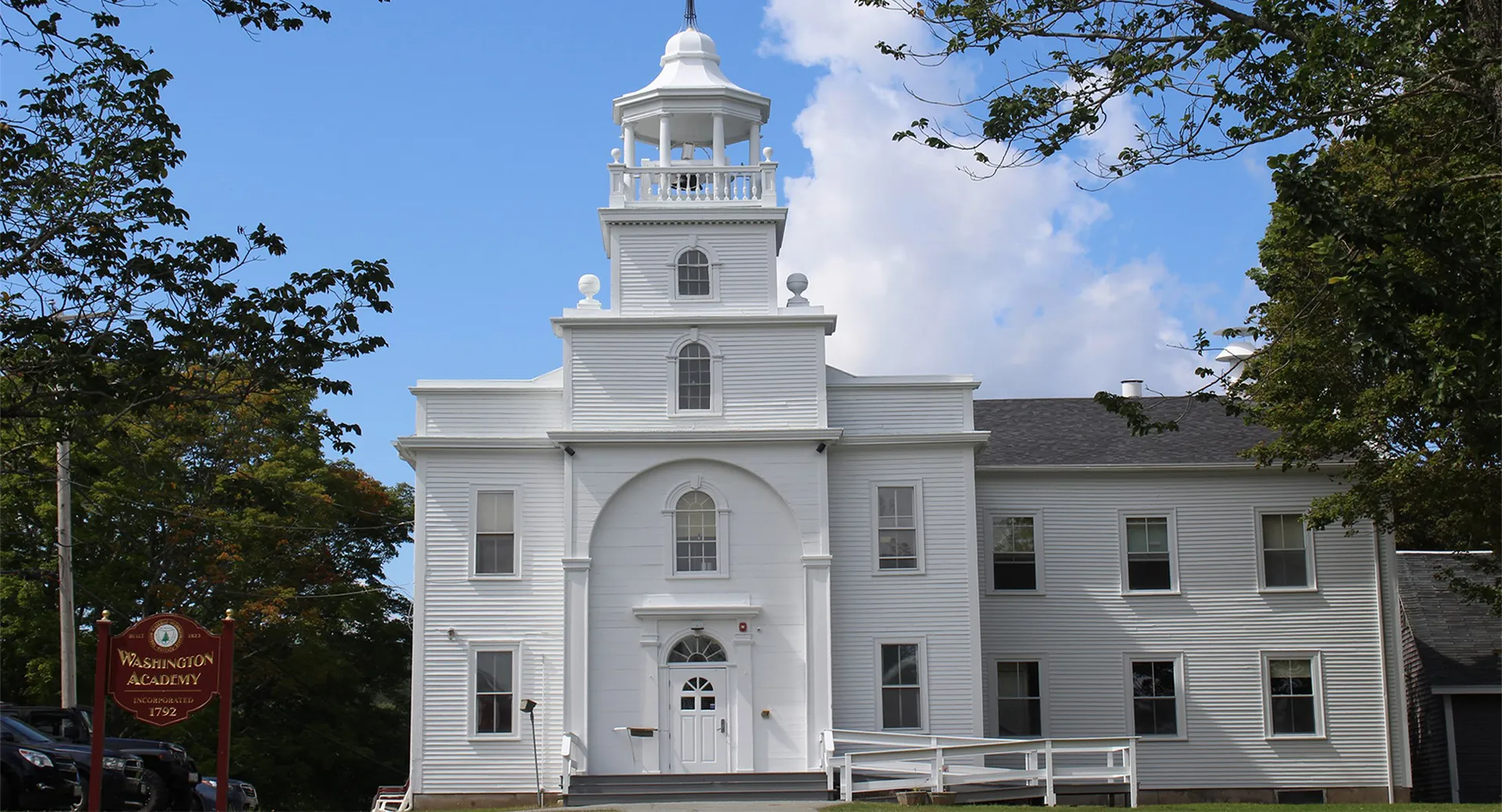 L'edificio principale bianco della Washington Academy con una torretta campanaria circondato da alberi.