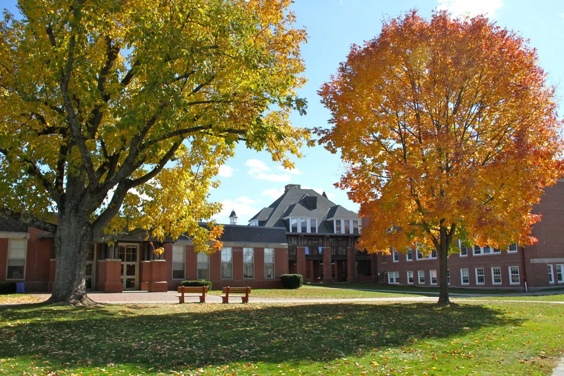 Edificio storico della Thornton Academy in un parco autunnale con alberi colorati e panchine sul prato.
