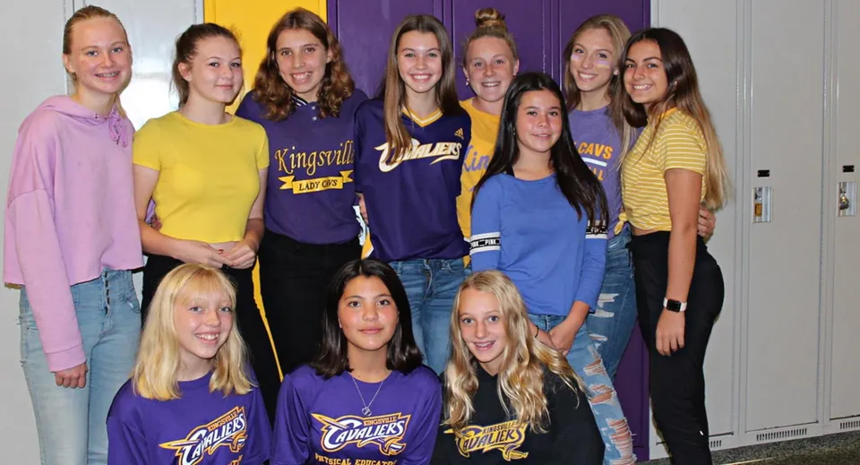 Un gruppo di studentesse posa davanti a uno sfondo colorato nel campus della Kingsville District High School.