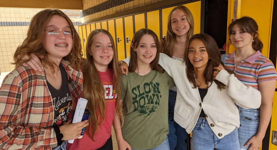 Un gruppo di giovani studentesse sta insieme nel corridoio della Arizona Lutheran Academy con gli armadietti sullo sfondo.