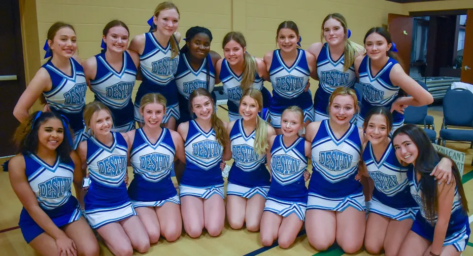 Un gruppo di giovani cheerleader in divisa blu e bianca posa insieme in una stanza del campus della Mackay North State High School.