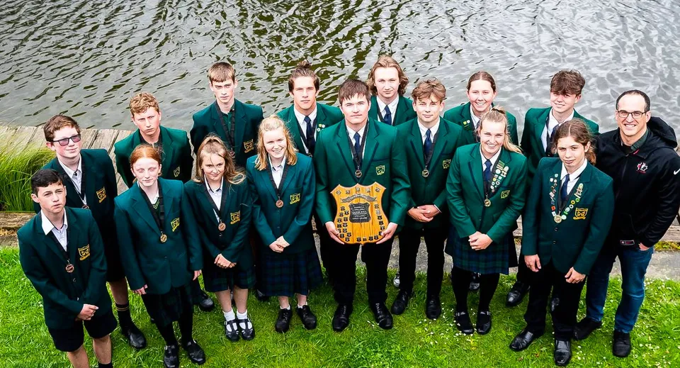 Studenti in divisa scolastica stanno insieme all'aperto vicino all'acqua nel campus del St. Peter's College.