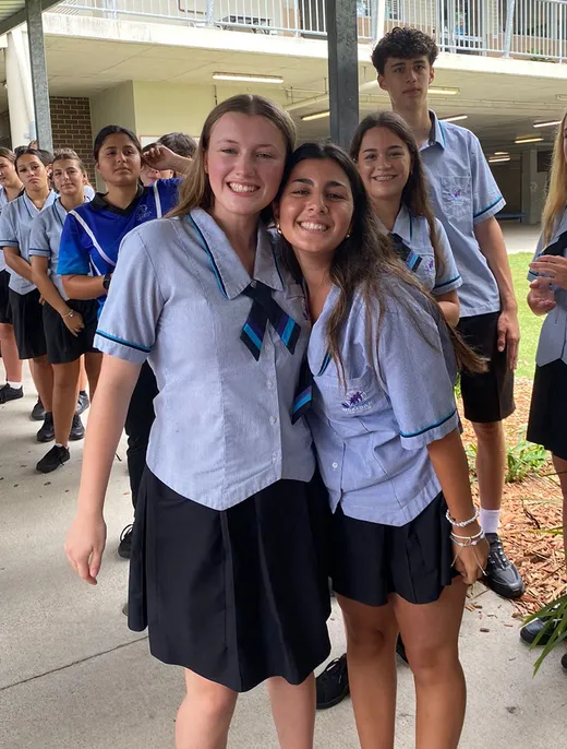 Dos estudiantes con uniforme escolar se abrazan en el patio del instituto