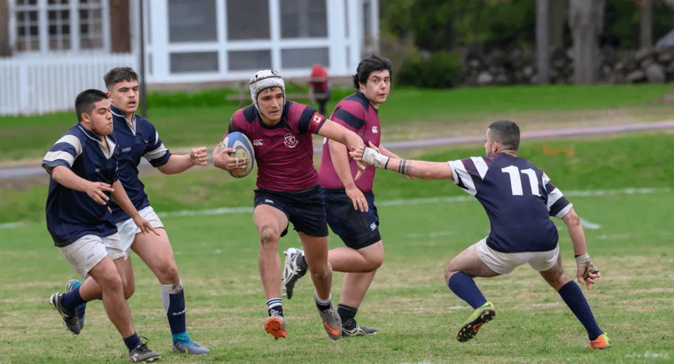 Gli studenti dell'Ashbury College giocano una partita di rugby sul campo davanti agli edifici scolastici.