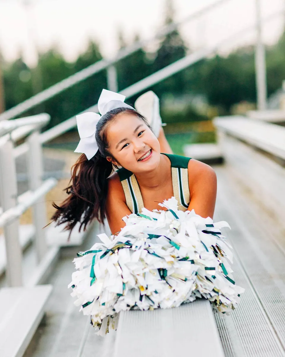 Una studentessa della Redmond High School con un fiocco bianco tra i capelli sorride davanti a uno sfondo verde.
