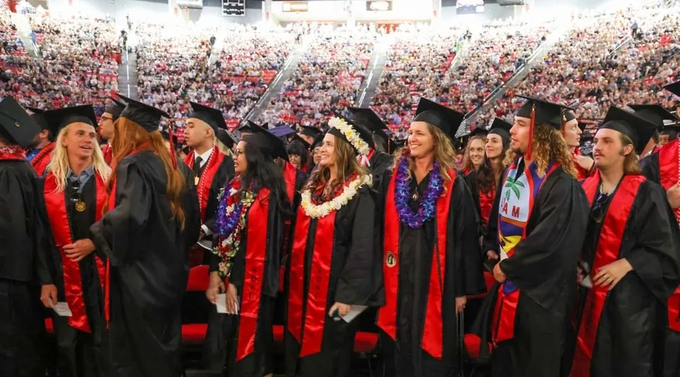 I laureati della San Diego State University sono insieme in toghe rosse e nere durante la cerimonia di laurea.