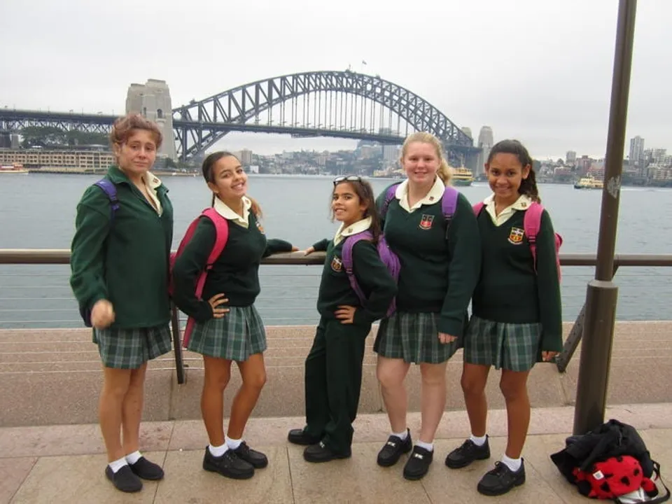Un gruppo di studentesse della Davidson High School posa davanti al Sydney Harbour Bridge con lo skyline della città sullo sfondo.