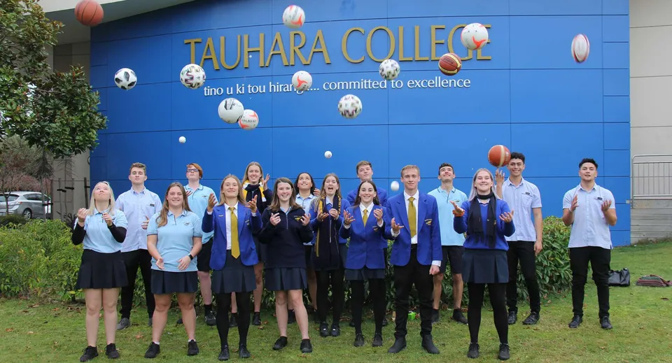 Un gruppo di studenti in divisa scolastica sta davanti alla parete blu con il logo del Tauhara College.