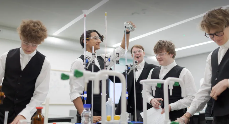 Un gruppo di studenti della Tonbridge School si trova in una stanza con apparecchiature e strumenti scientifici sullo sfondo.