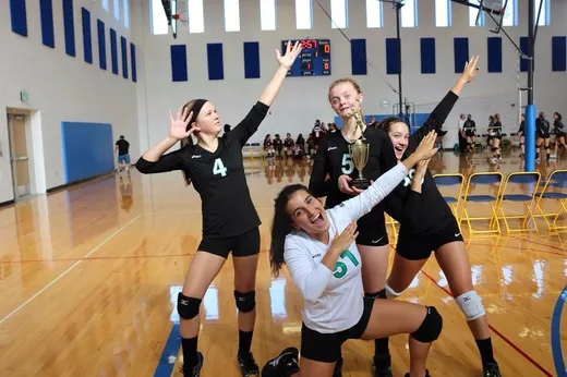 Squadra di pallavolo femminile festeggia con una coppa in palestra