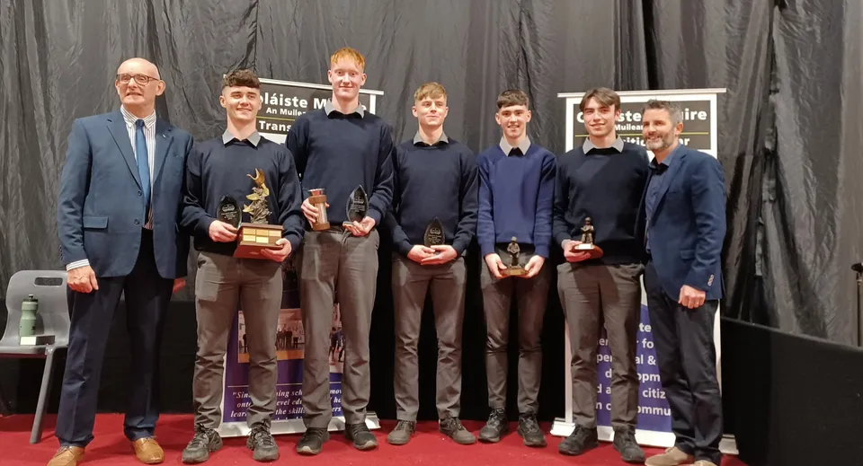 Un gruppo di persone in abiti formali si trova sul palco del Coláiste Mhuire Mullingar.